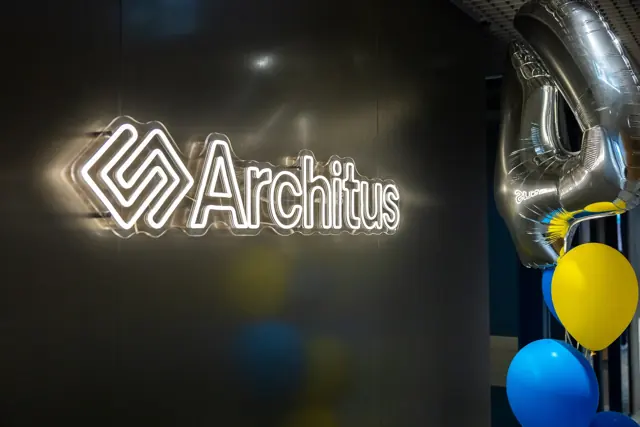 Baltas LED neoninis įmonės logotipas ant tamsios biuro sienos