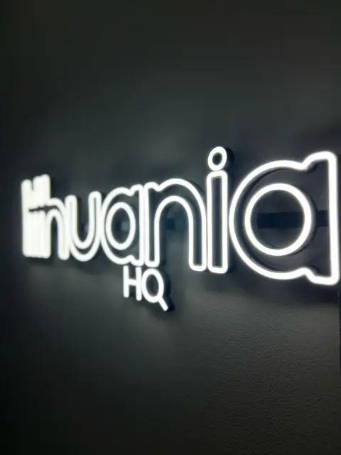 Baltas LED neoninis logotipas ant tamsios sienos