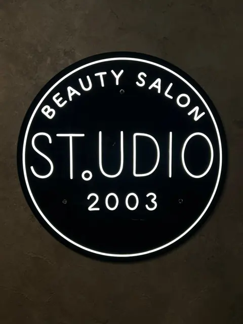 Baltas LED neoninis grožio salono logotipas ant juodo apskrito pagrindo