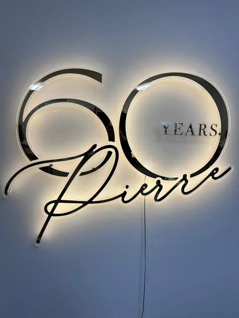 Jubiliejaus užrašas „60 years“ su LED galiniu apšvietimu ant šviesios sienos