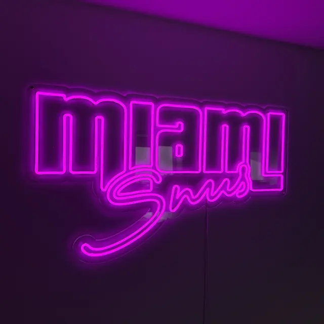 Magenta LED neoninis prekės ženklo užrašas ant tamsios sienos