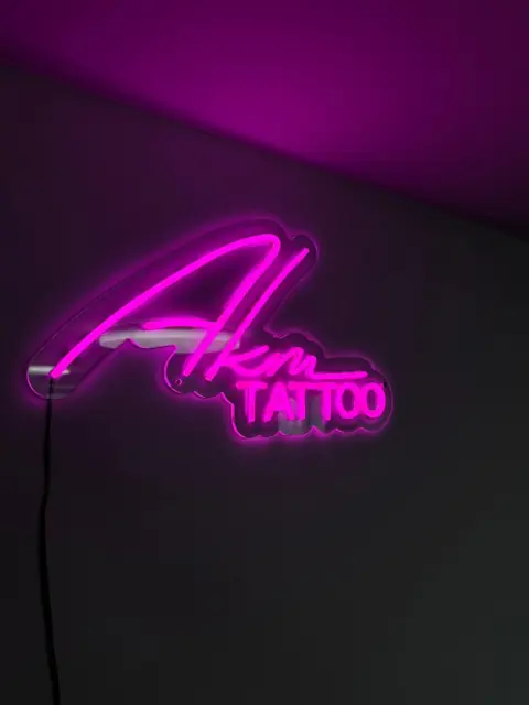 Rožinis LED neoninis tatuiruočių studijos logotipas rašytiniu šriftu